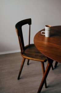 primer plano de una mesa y una silla de madera con taza encima