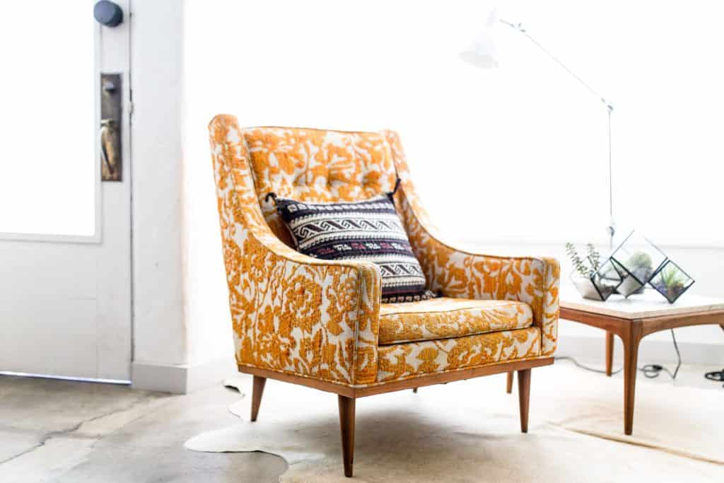 sillón estampado mostaza en sala de tonalidades blancas